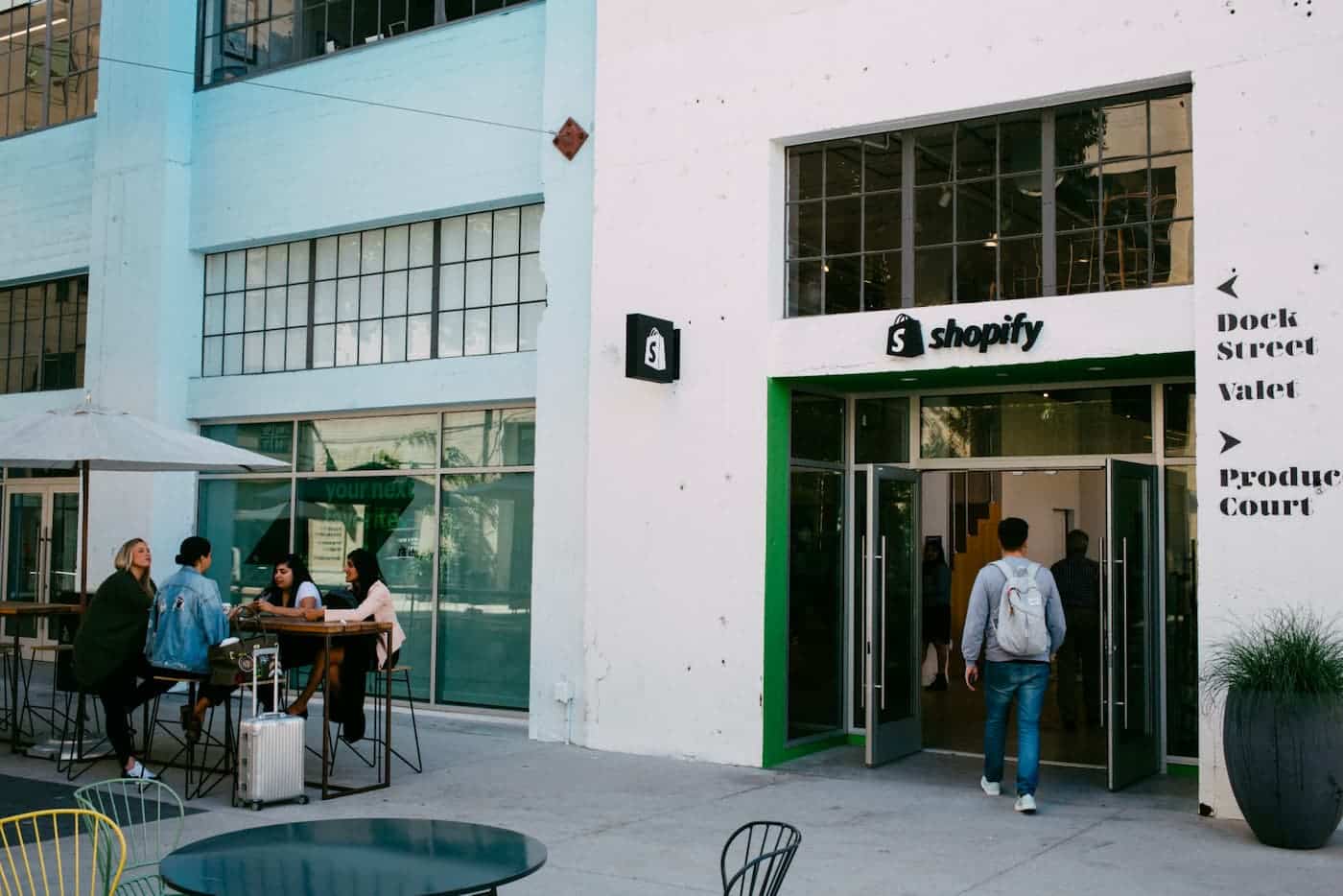 A photo of a white building with the Shopify logo on top of the doorframe